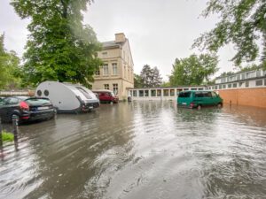 Der Parkplatz des Schulgebäudes "Lindweiler Hof" während des verheerenden Hochwassers am 14. Juli 2021. Die Künstlerinnen und Künstler in Köln-Bickendorf setzen sich für eine Retentionsmulde "Kradepohl" als Hochwasserschutz ein.